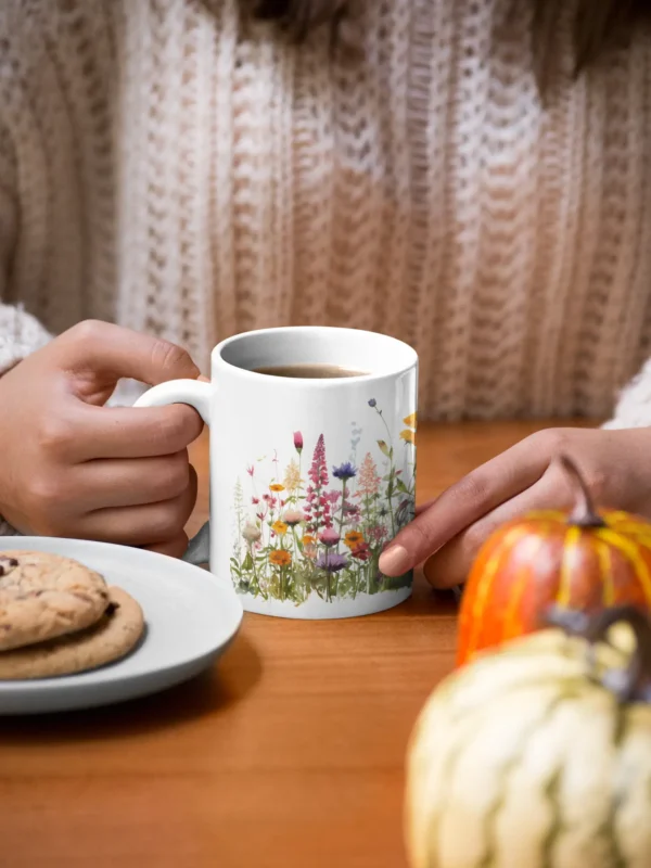 mockup of a woman holding an 11 oz mug with cookies and pumpkins at the table 29136 1