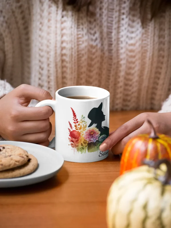 mockup of a woman holding an 11 oz mug with cookies and pumpkins at the table 29136